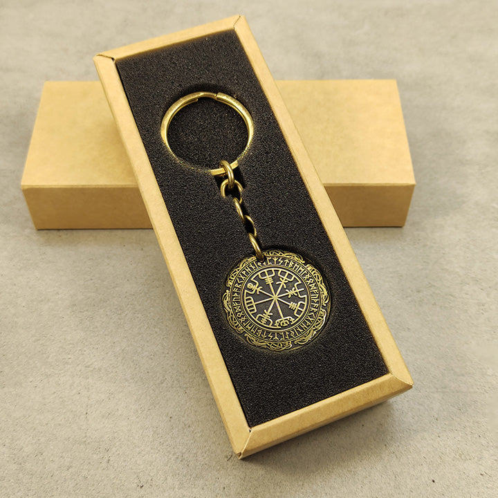 Vertical view of a brass Vegvisir coin keychain in a premium black gift box insert, showcasing the polished brass surface and engraved nordic details.