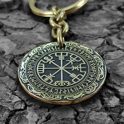 Personalized brass Runic Compass keychain on a rustic dark wood bark texture, highlighting the antique finish and durable metal quality of the talisman.