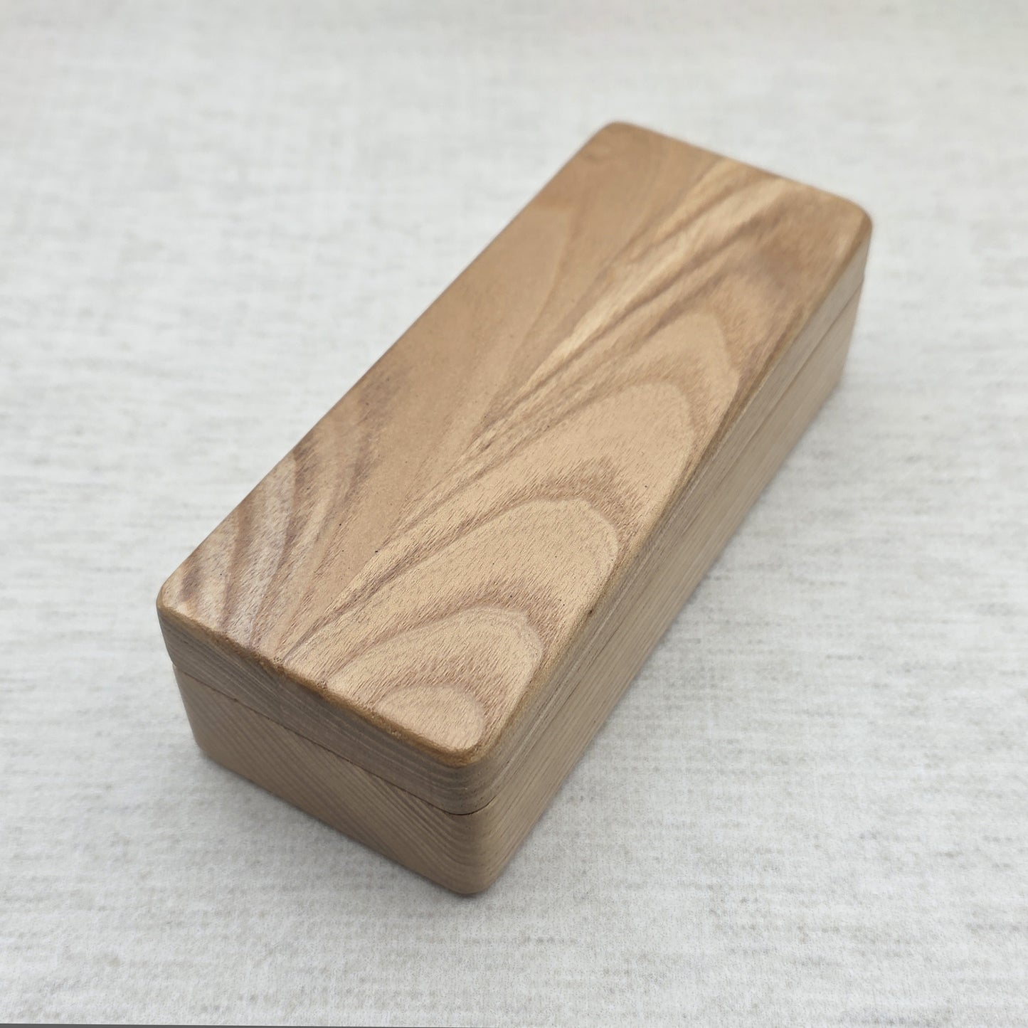 Top perspective view of closed rectangular ash wood keychain gift box with natural wood grain finish