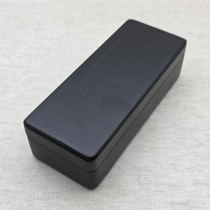 Closed black solid ash wood display box top perspective view showing smooth rounded corners and wood grain