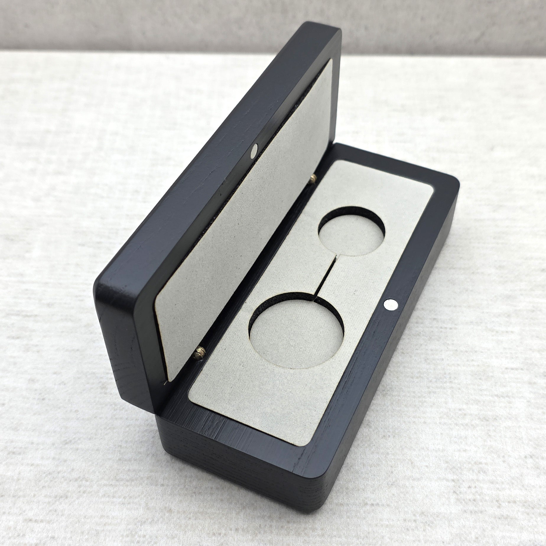 Handcrafted black ash wood gift box open at an angle showing light gray velvet insert with double cutout for keychain or pendant necklace
