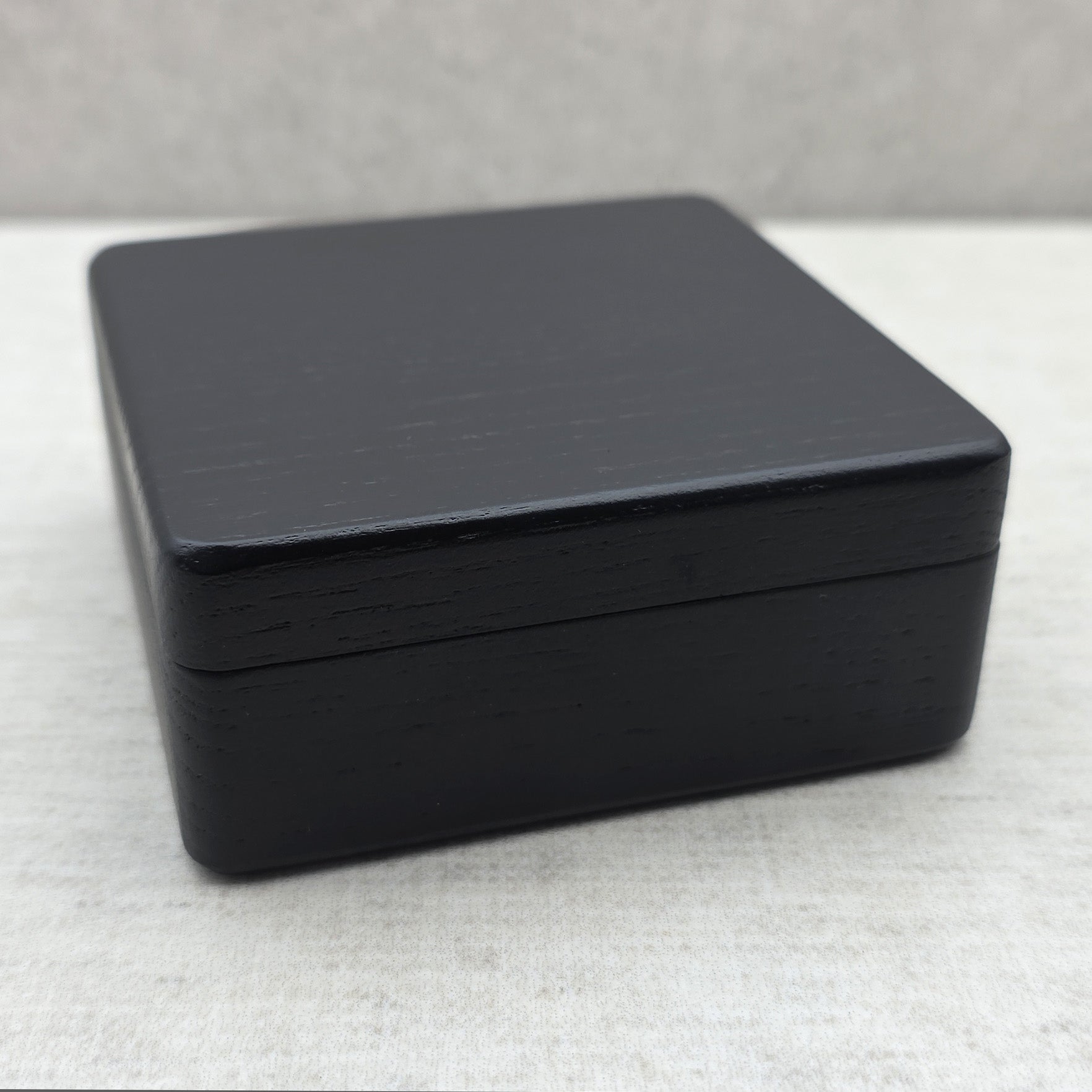 Front perspective of closed black wooden presentation box, compact storage case for collectable coins, jewelry pendants, and medals.