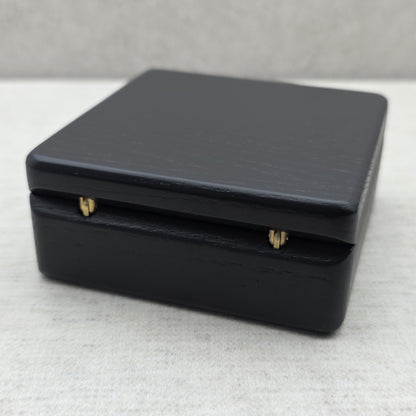 Rear view of closed black ash wood coin box highlighting two sturdy golden brass metal hinges for smooth opening and durability.