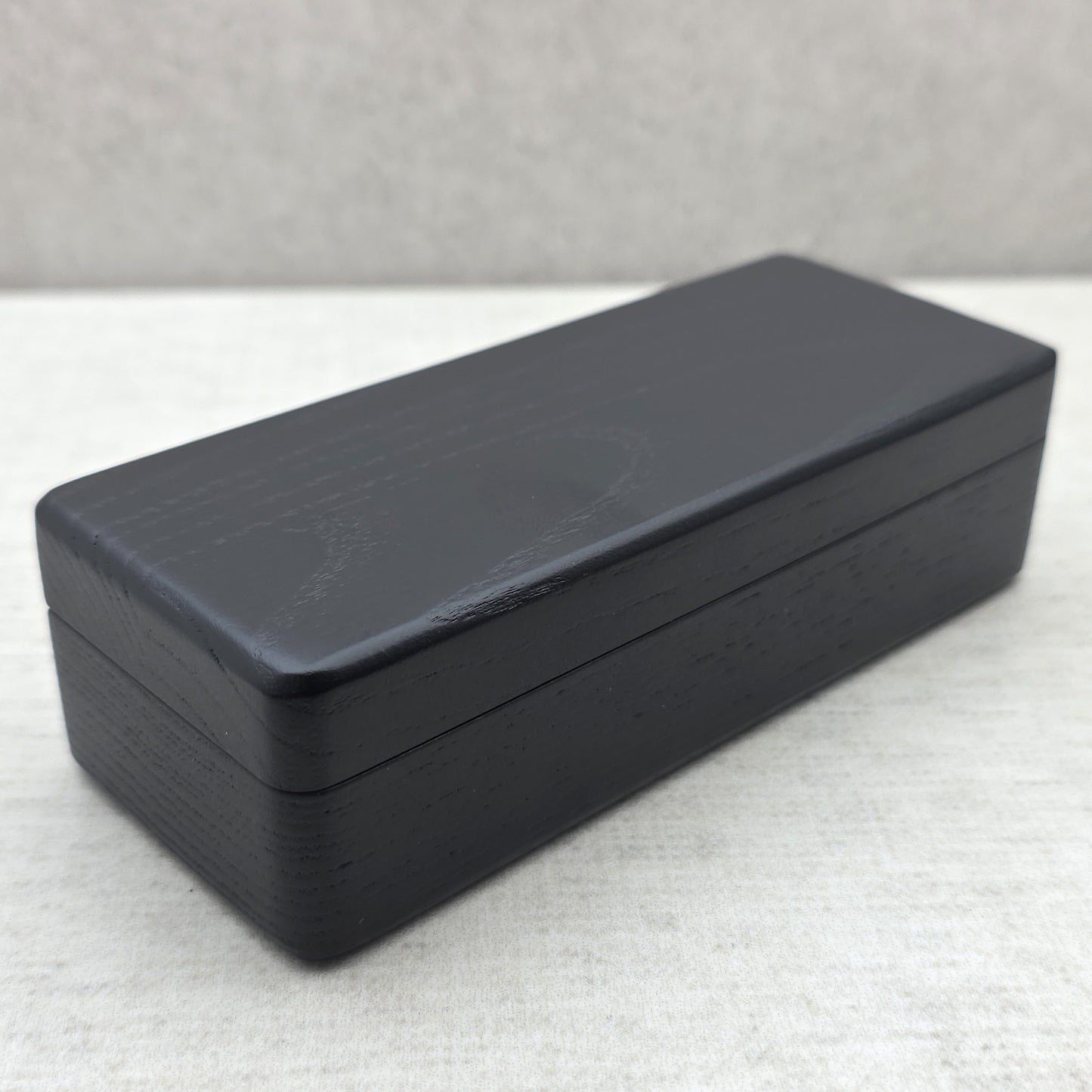 Closed black ash wood gift case side view showing sleek black finish and solid wood construction