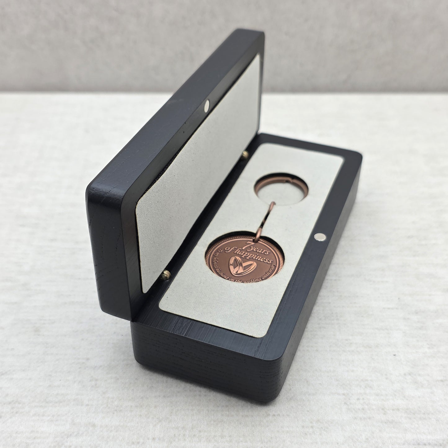 Open black ash wood gift box with personalized keychain placed inside light gray velvet insert