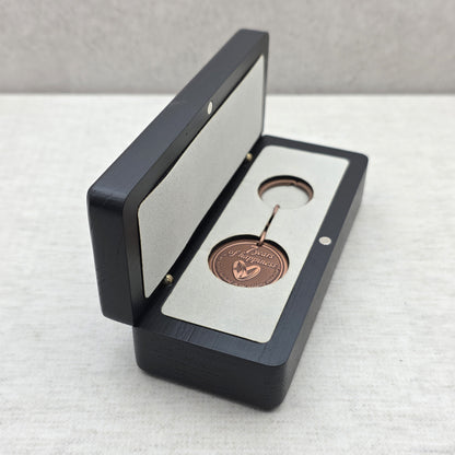 Open black ash wood gift box with personalized keychain placed inside light gray velvet insert
