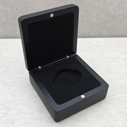 High angle view of open black wooden gift box featuring matching solid black velvet-covered foam insert for challenge coins and medals.