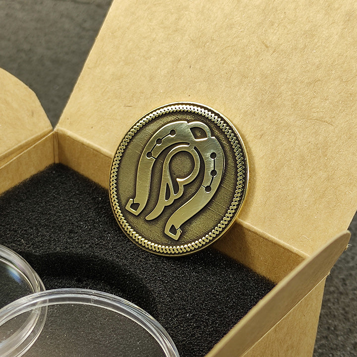 Handcrafted brass talisman coin with lucky horseshoe symbolism placed on a craft paper box.