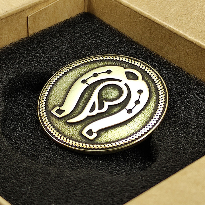 Top view of a custom engraved brass coin in a premium gift box with black foam insert, showcasing deep relief details.