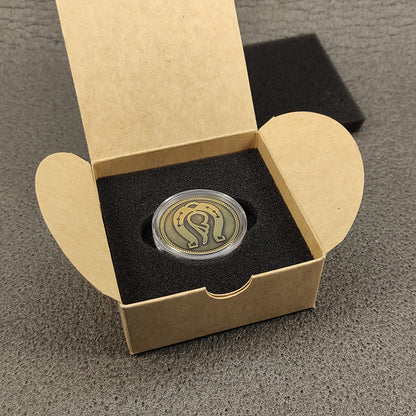 Brass personalized gift coin in an open cardboard box with protective lining, ready for gifting.
