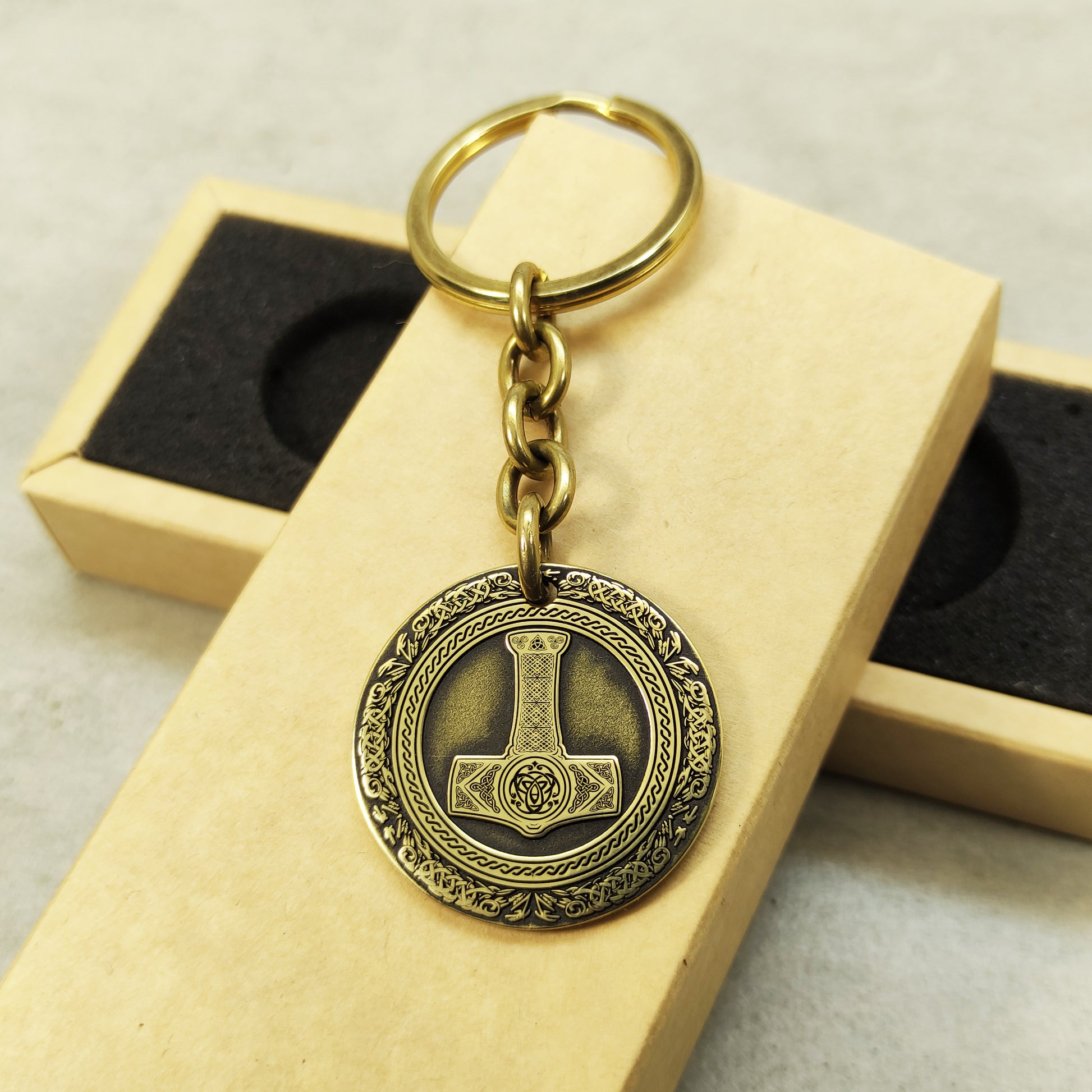 Detailed view of the brass Thor's Hammer medal, highlighting the intricate Mjolnir illustration and dark recessed patina engraving in 32mm diameter.