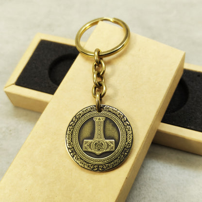 Detailed view of the brass Thor's Hammer medal, highlighting the intricate Mjolnir illustration and dark recessed patina engraving in 32mm diameter.