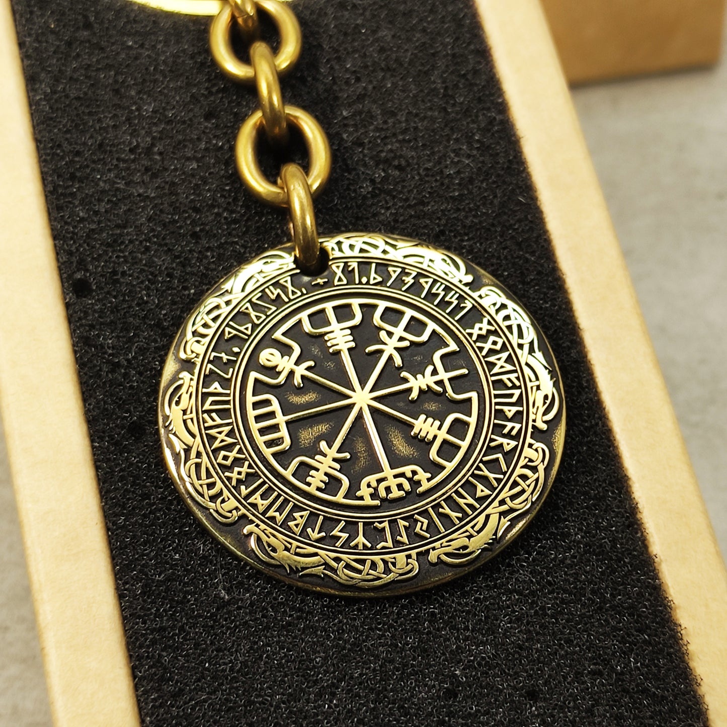 Detailed view of the brass Runic Compass coin, highlighting the intricate Vegvisir symbol and dark recessed patina engraving for high contrast.