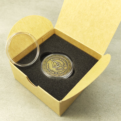 Personalized brass souvenir coin in clear protective case next to a minimalist cardboard gift packaging for wedding anniversary.