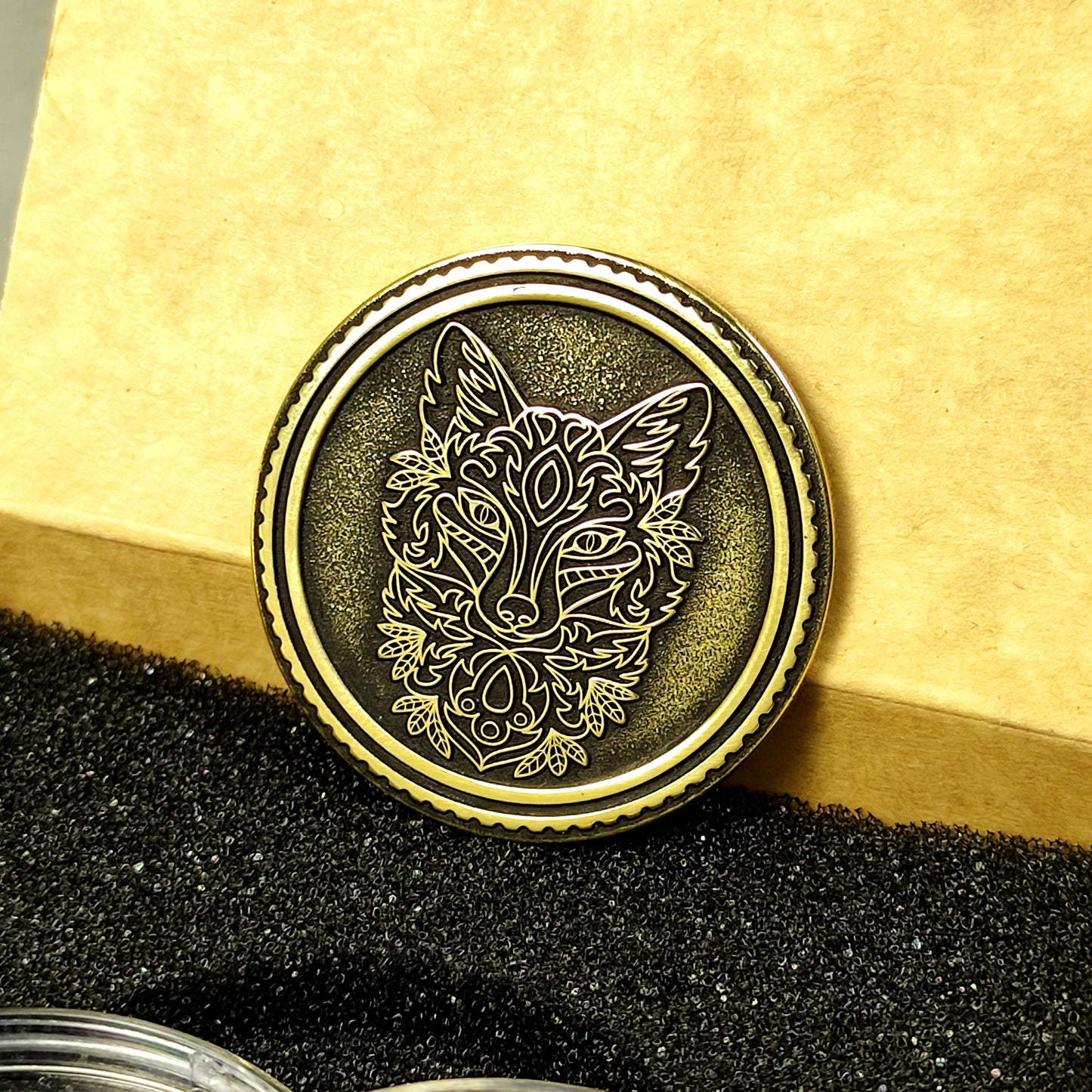 Detailed macro shot of an engraved brass coin with fox design, showing the high-quality metal finish and deep relief carving.