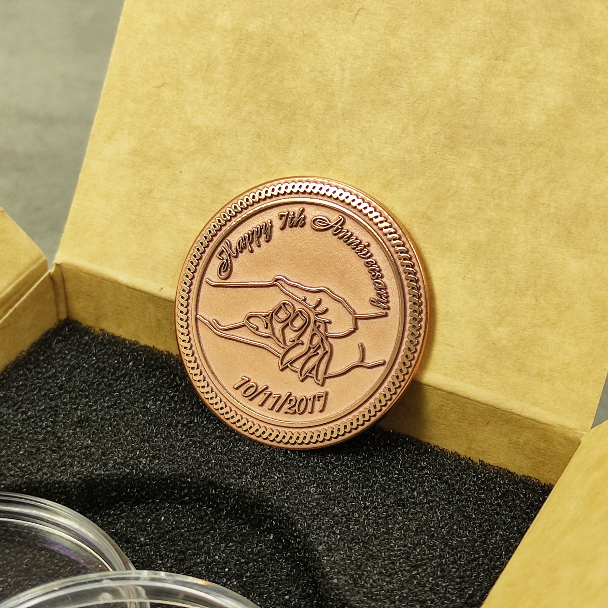 Engraved copper anniversary coin for 7 years of marriage, personalized gift inside a craft paper box with foam insert, obverse view.