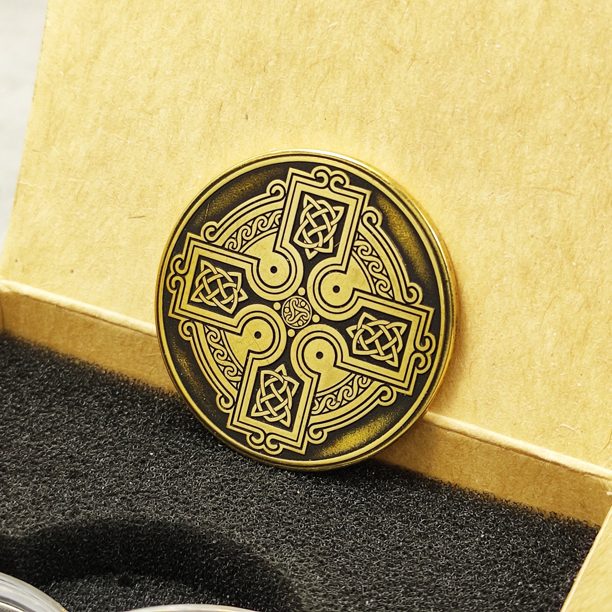 Perspective view of a personalized brass Celtic coin in a premium gift box, solid 2mm thick handcrafted metal souvenir.