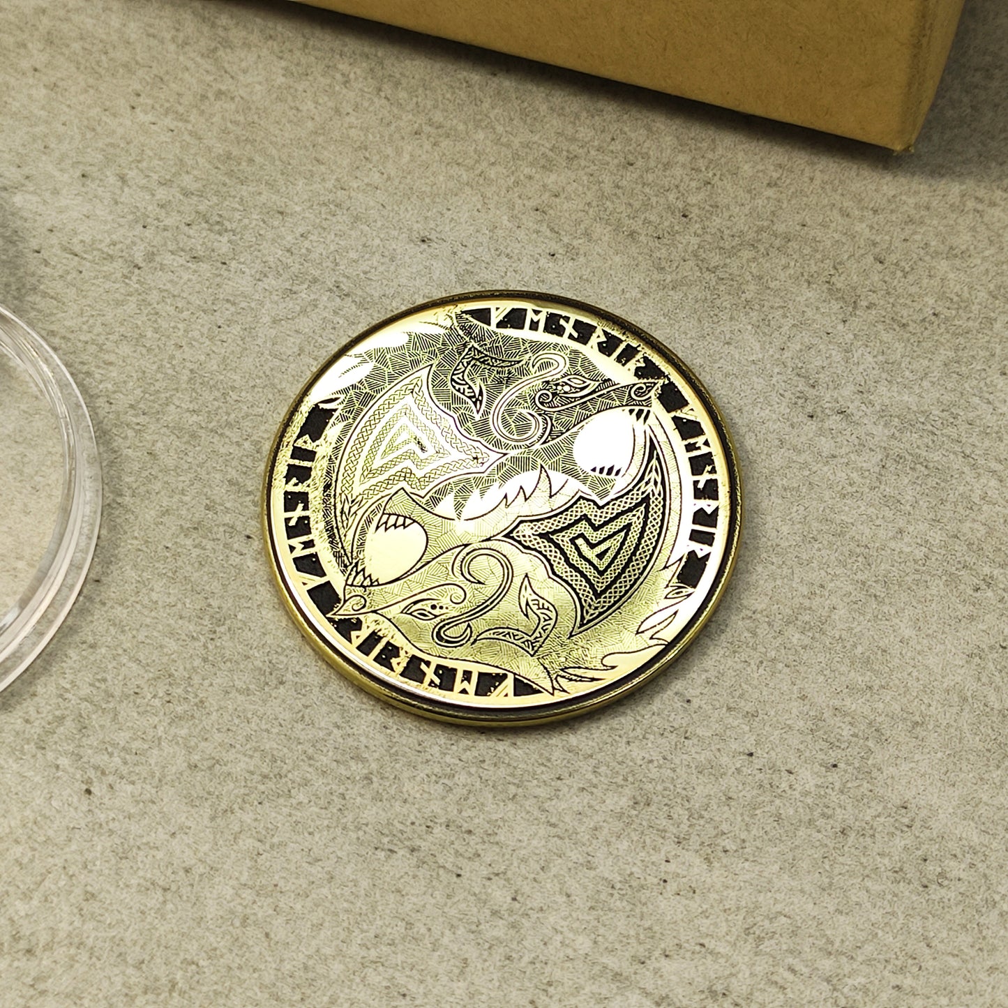 Close-up of a 2mm thick brass challenge coin with Norse wolf design, showcasing metallic luster and precision etching.