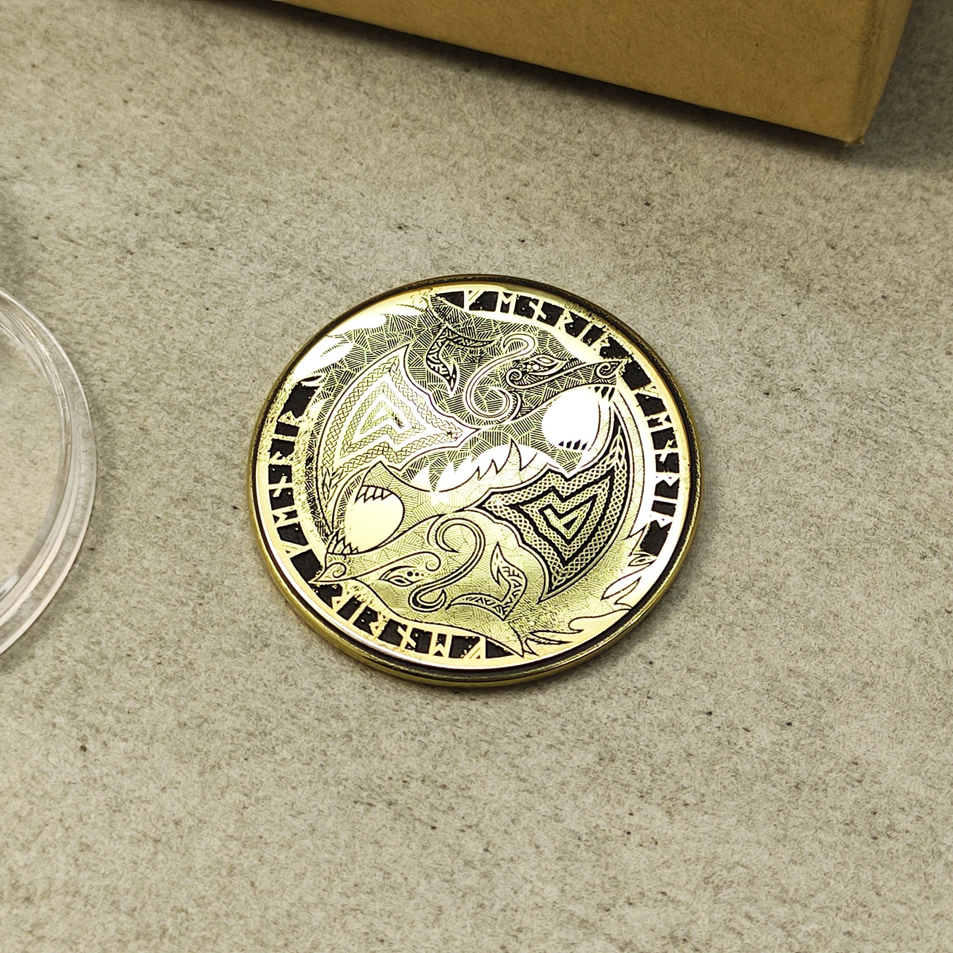 Close-up of a 2mm thick brass challenge coin with Norse wolf design, showcasing metallic luster and precision etching.