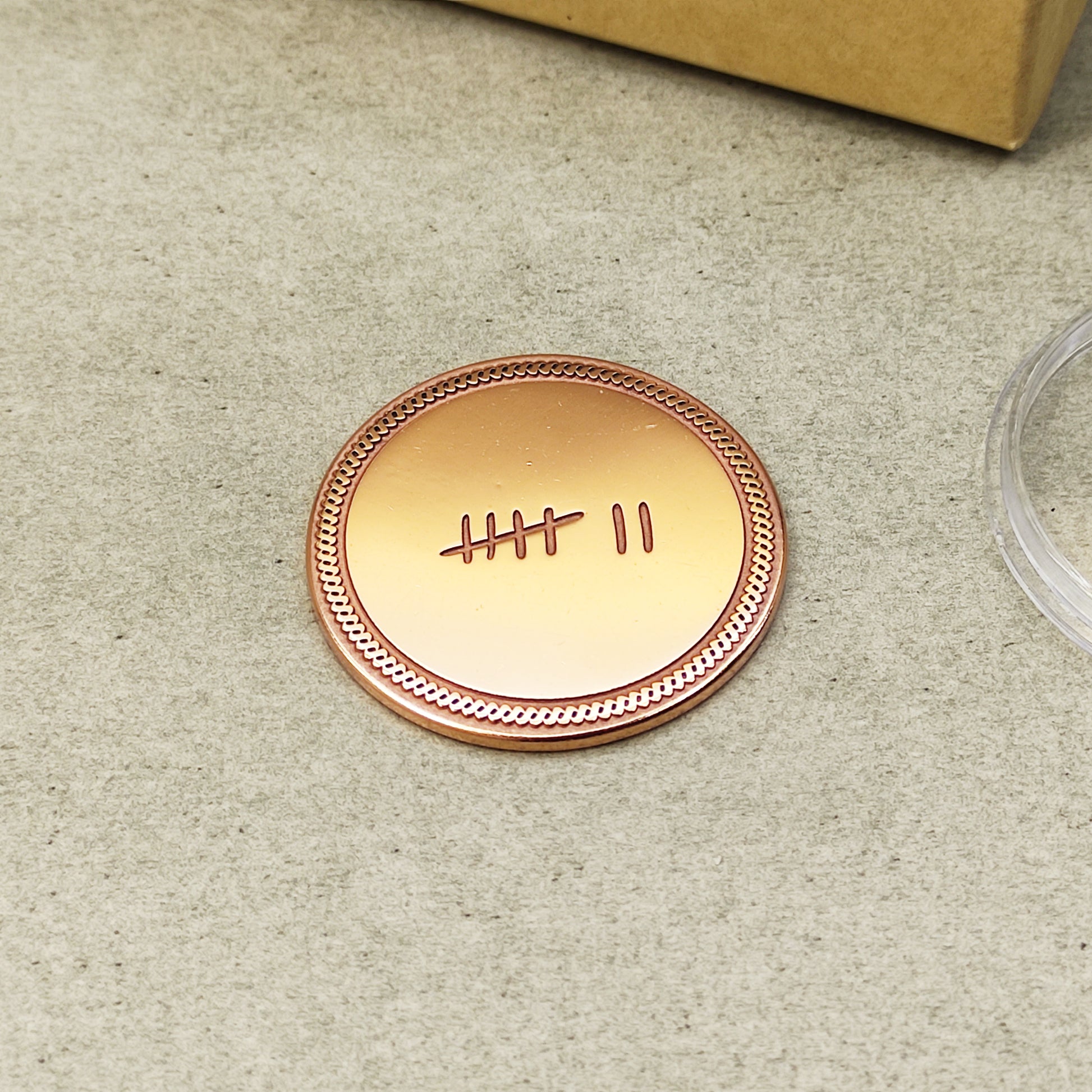 Minimalist 7 year anniversary copper token, hand-polished metal coin with decorative border and engraved tally symbols.