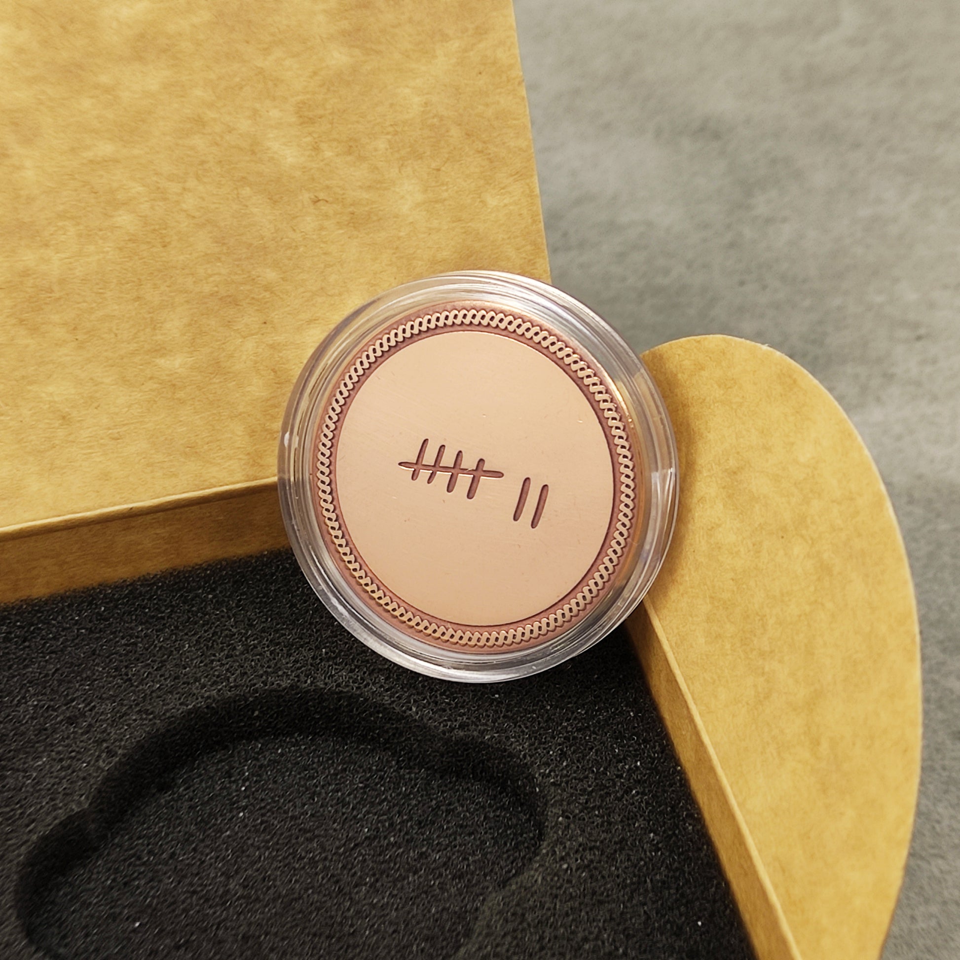 Engraved copper anniversary token in a clear protective acrylic capsule, personalized 7th anniversary gift packaging.