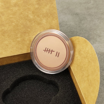Engraved copper anniversary token in a clear protective acrylic capsule, personalized 7th anniversary gift packaging.