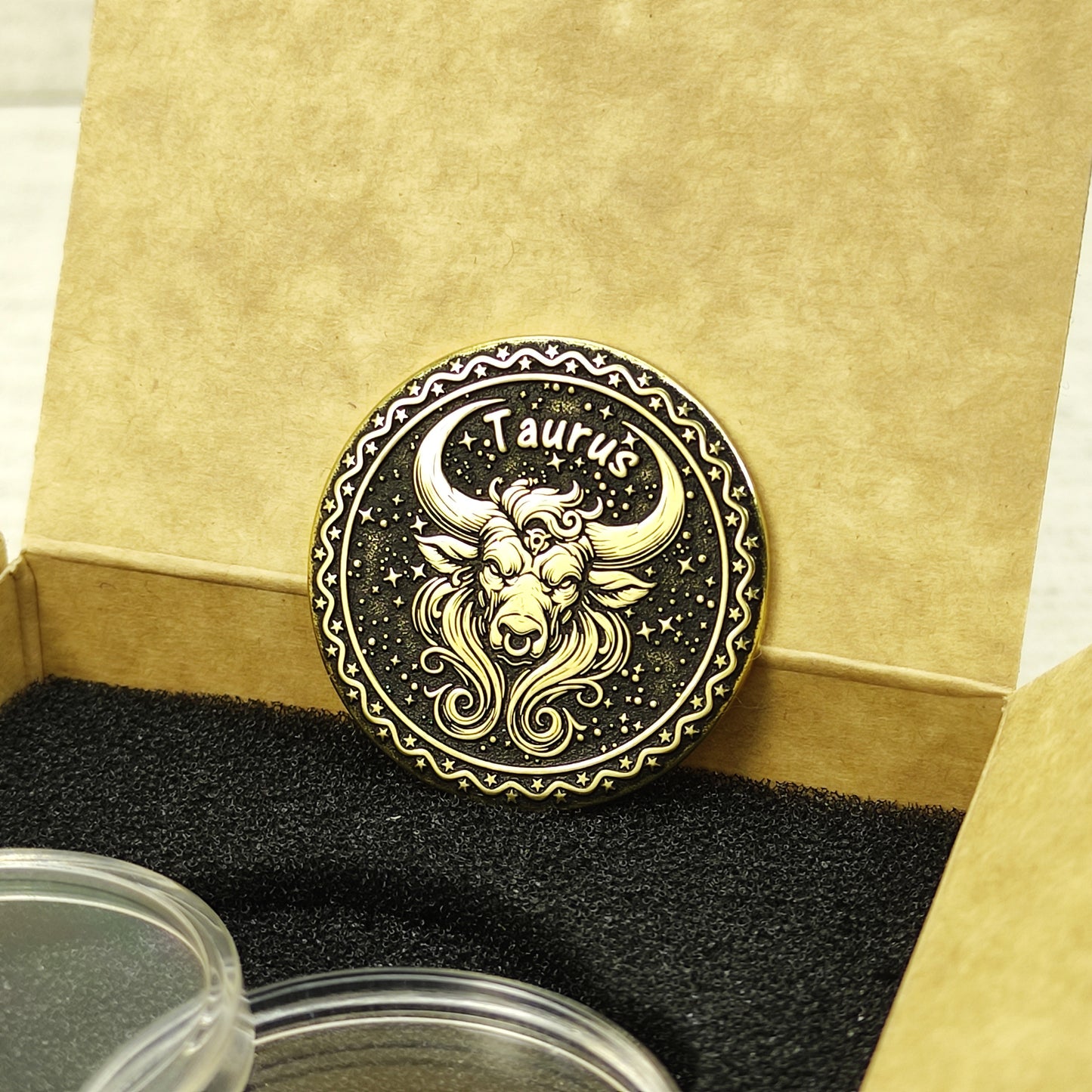 Custom Taurus zodiac brass coin in a premium gift box with black foam insert, highlighting the gold-tone brass material and dark engraved details.