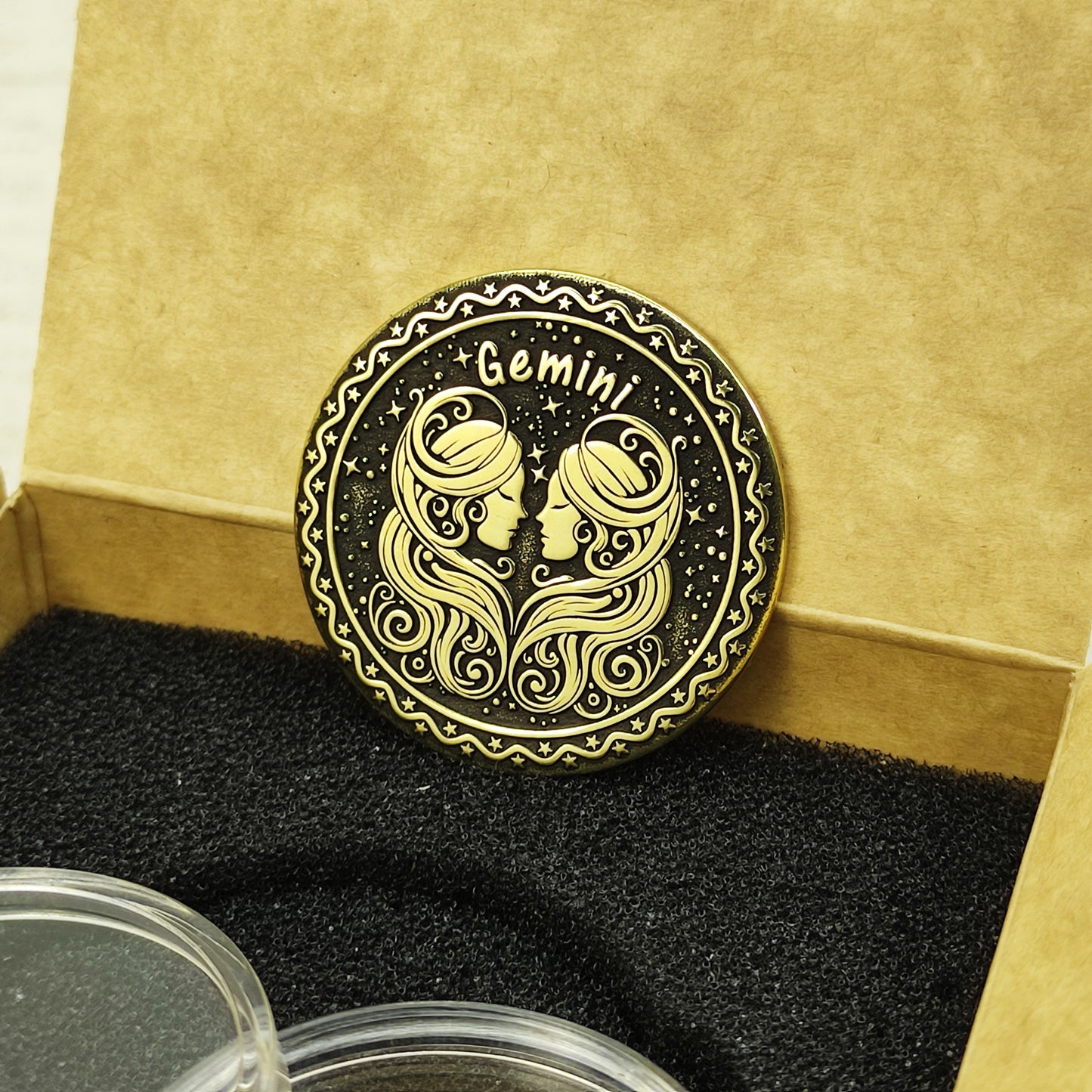 Custom Gemini zodiac brass coin in a premium gift box with black foam insert, highlighting the gold-tone brass material and dark engraved details.