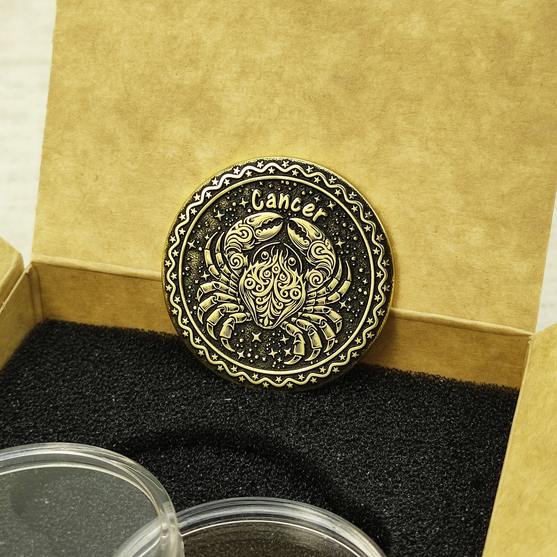 Custom Cancer zodiac brass coin in a premium gift box with black foam insert, highlighting the gold-tone brass material and dark engraved details.