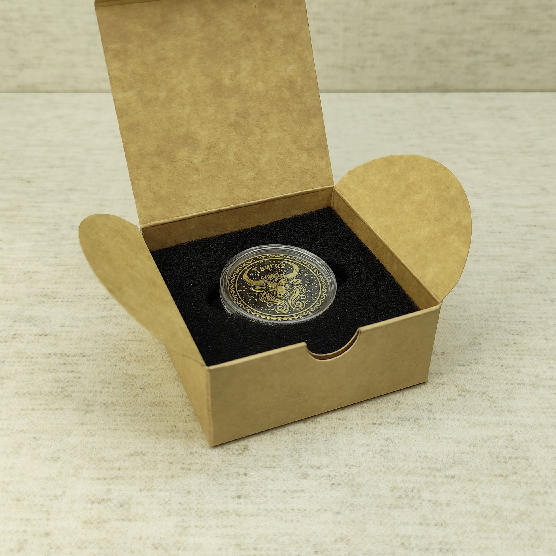 Taurus zodiac brass medal in a small square craft gift box, professional presentation of a personalized astrology souvenir with dark patina finish.