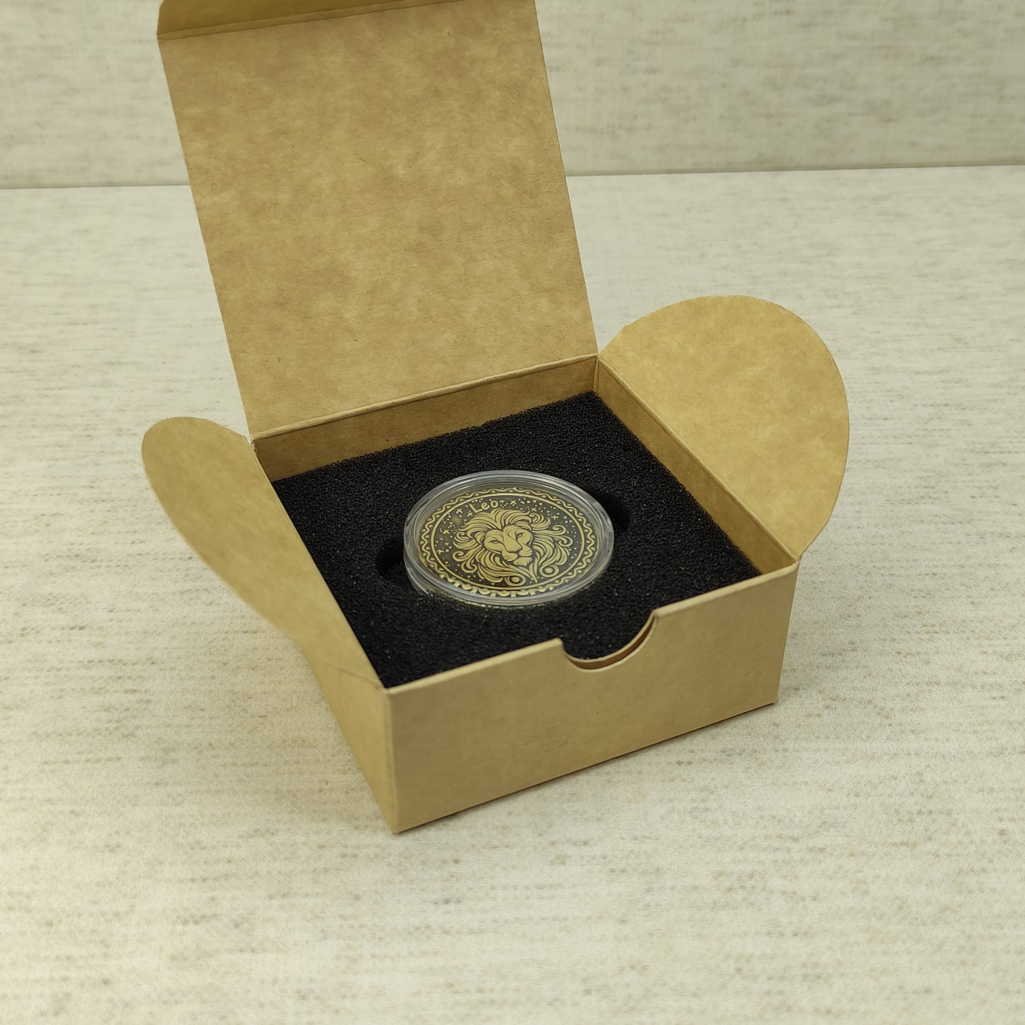 Leo zodiac brass medal in a small square craft gift box, professional presentation of a personalized astrology souvenir with dark patina finish.