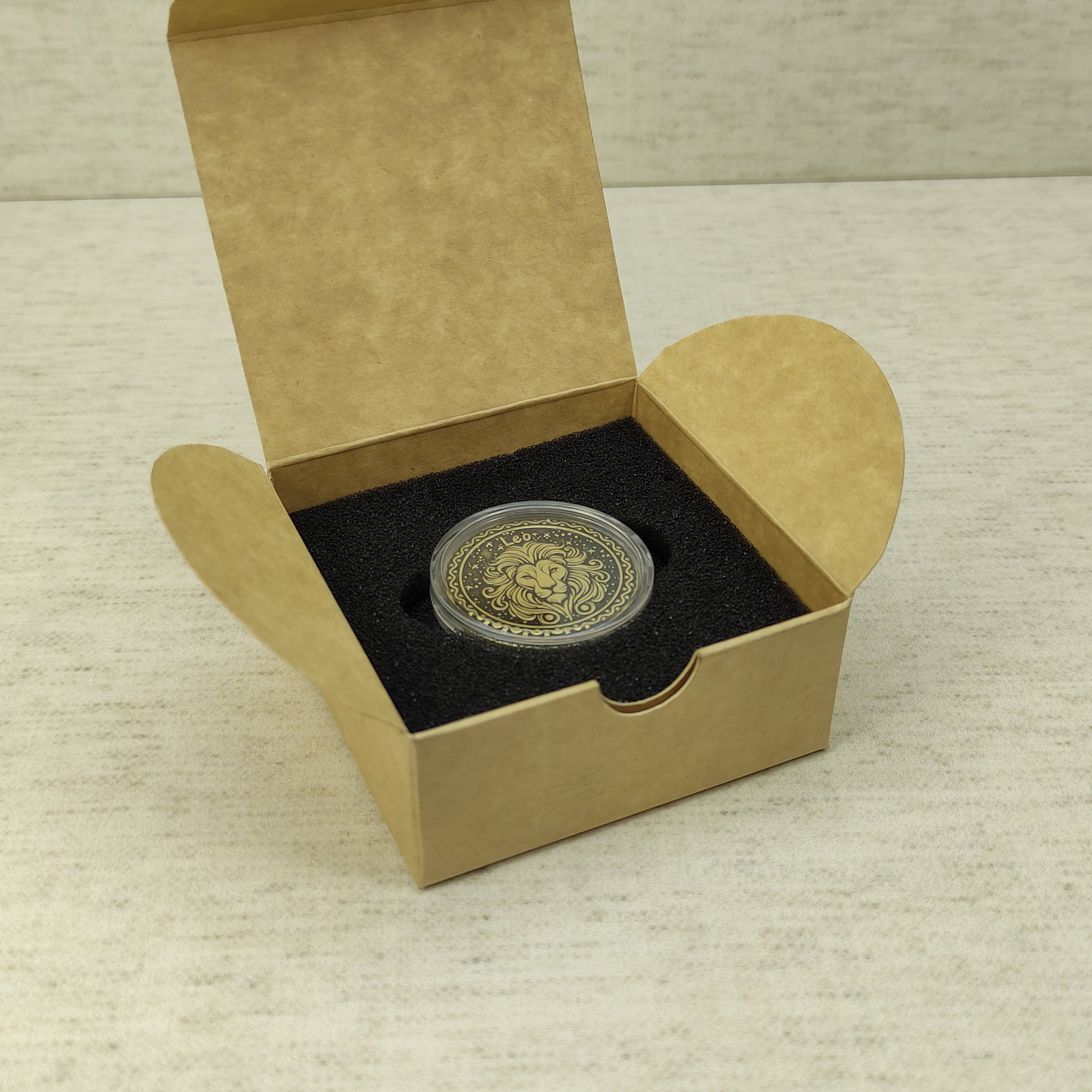 Leo zodiac brass medal in a small square craft gift box, professional presentation of a personalized astrology souvenir with dark patina finish.