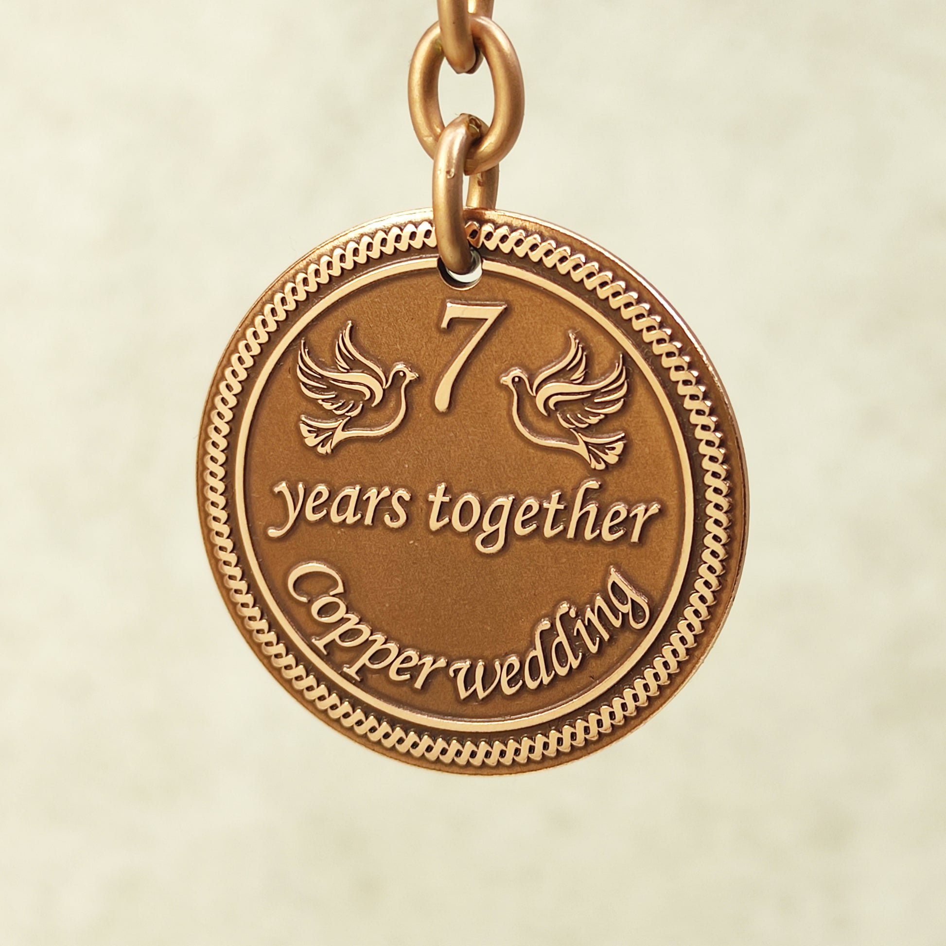 Close-up of handcrafted copper coin pendant for 7 years together with ornate borders and vintage patina.