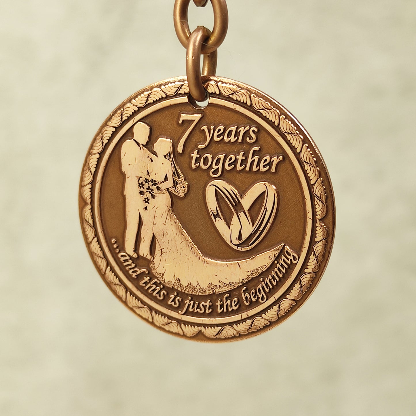 Pure copper 7th anniversary souvenir keychain, personalized romantic gift with decorative border and antique patina, obverse view.