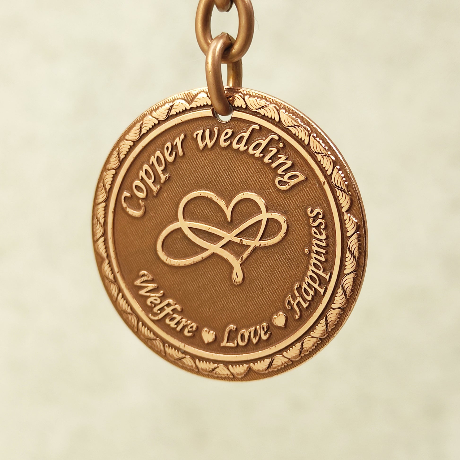 Close-up of handcrafted copper anniversary coin pendant featuring intricate infinity symbol and vintage patina.