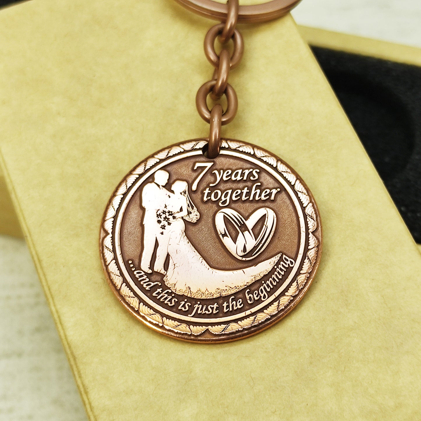 Artisan crafted copper anniversary keychain, "7 years" personalized token with wedding rings design, high-quality metal engraving.