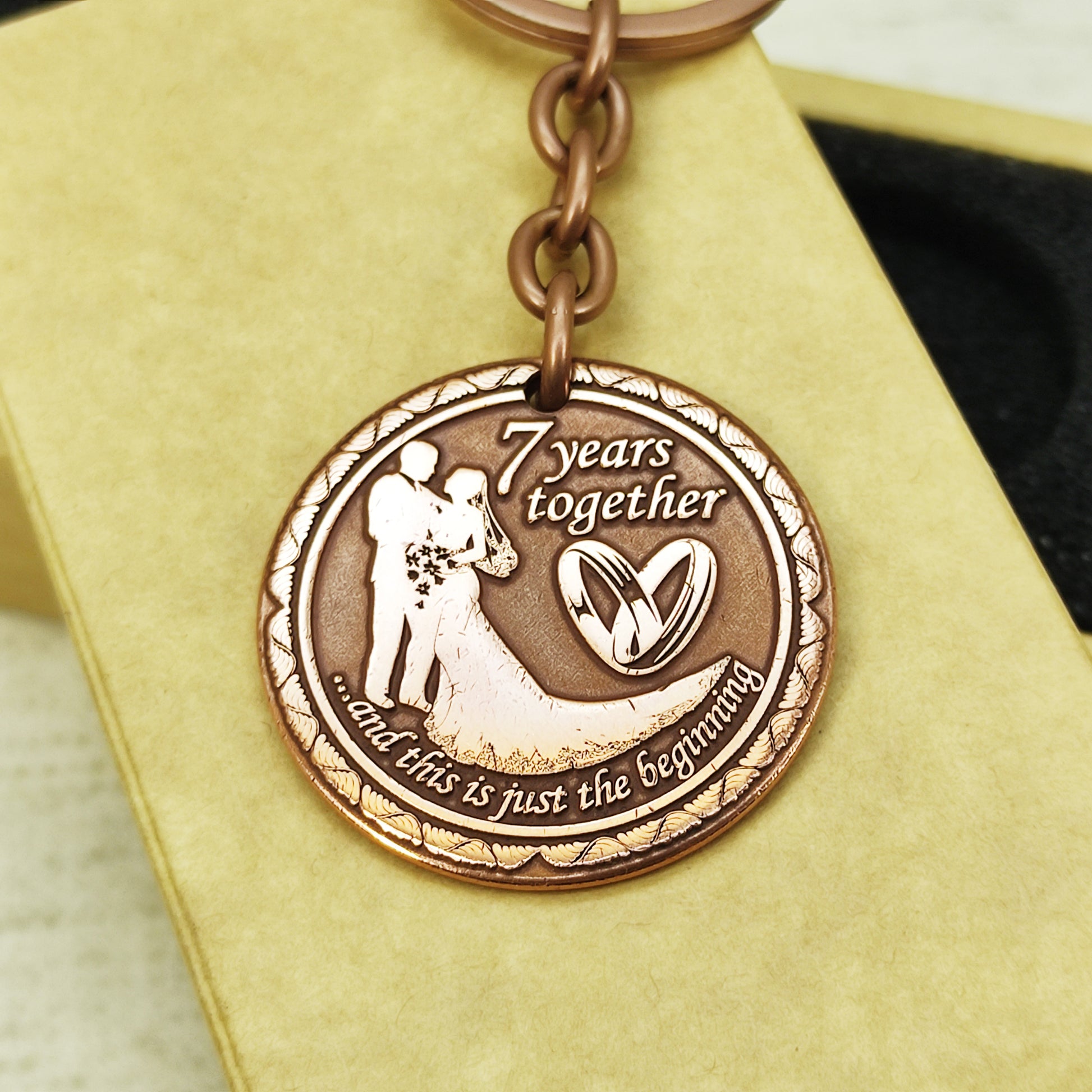 Artisan crafted copper anniversary keychain, "7 years" personalized token with wedding rings design, high-quality metal engraving.