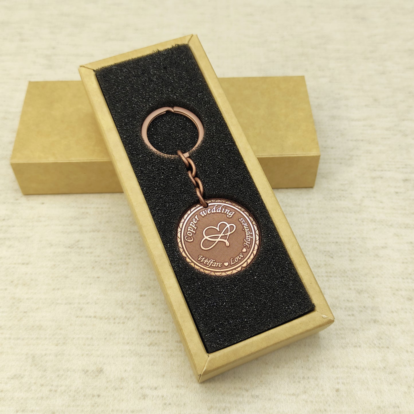 Customized copper wedding anniversary keychain presented in an elegant black foam insert gift box.