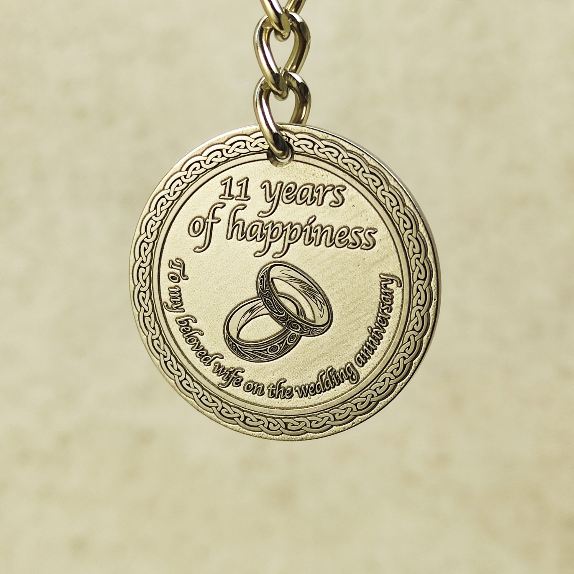 Detailed macro shot of engraved brass anniversary coin, showcasing high-precision laser etching and decorative celtic border on a 32mm metal keychain.