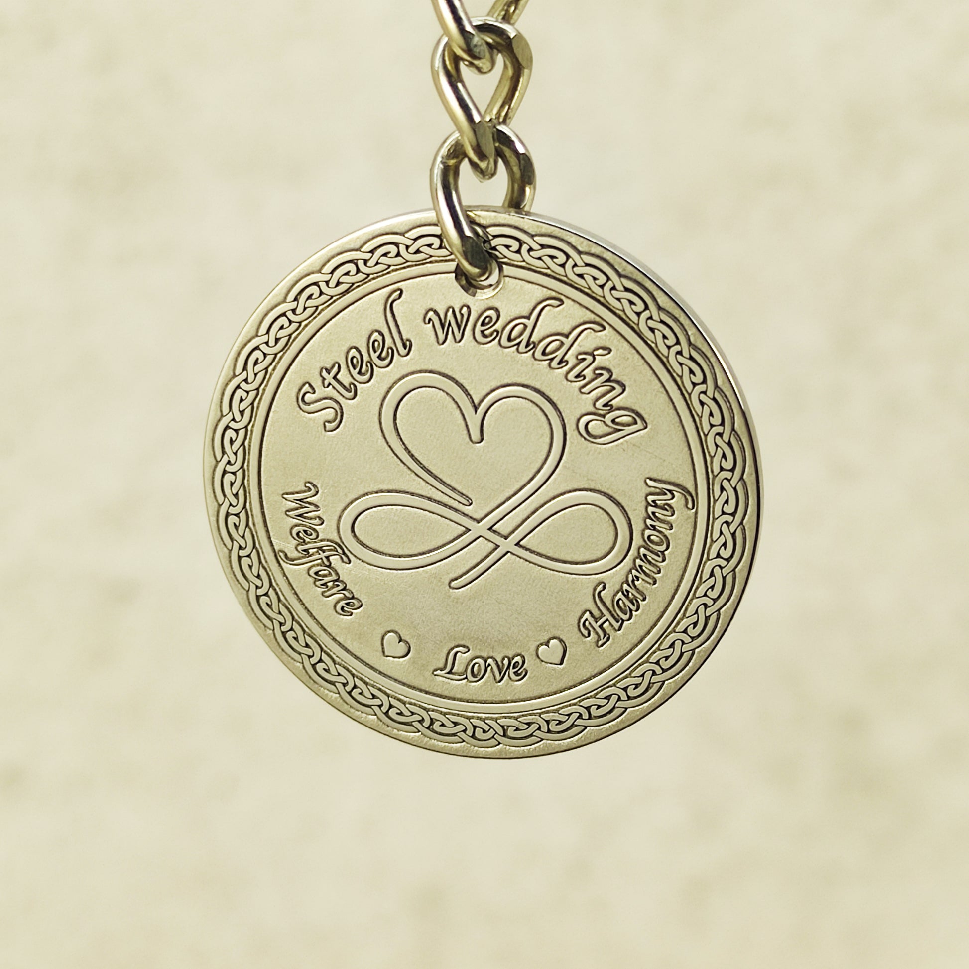 Close-up of handcrafted stainless steel coin pendant for steel anniversary featuring decorative circular borders.