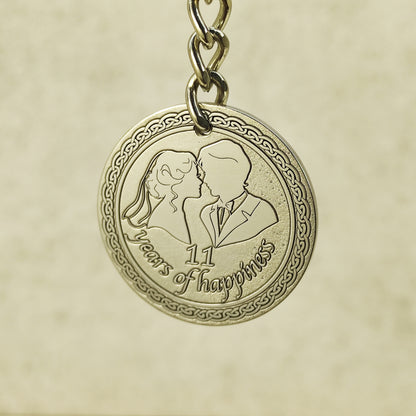 Detailed macro shot of engraved stainless steel coin for 11th anniversary, featuring 3D-style engraving of a husband and wife with decorative celtic border.