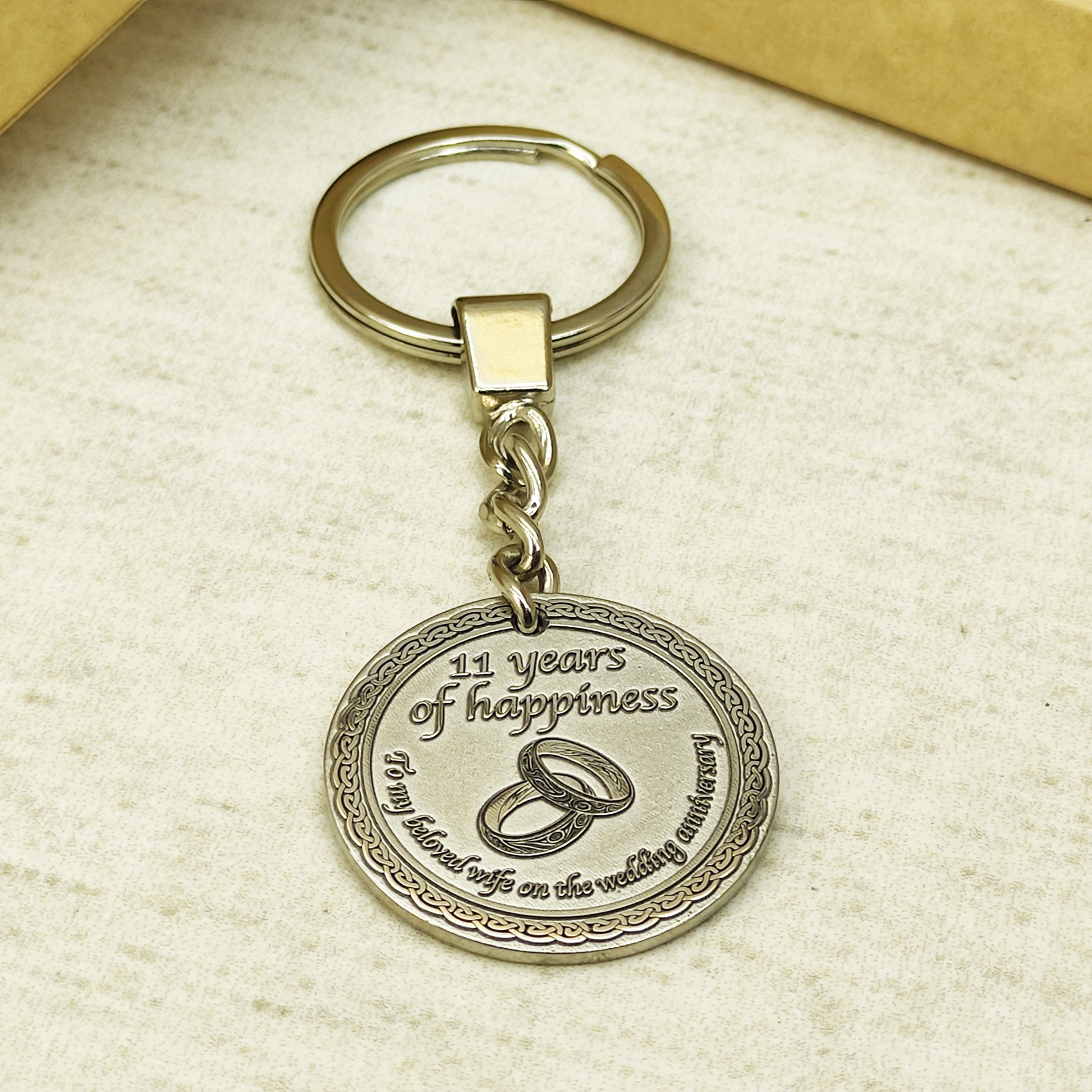Brass anniversary keychain with steel ring and chain, showcasing sturdy hardware and professional patina treatment on the engraved metal coin.