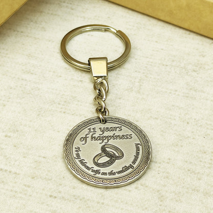 Brass anniversary keychain with steel ring and chain, showcasing sturdy hardware and professional patina treatment on the engraved metal coin.