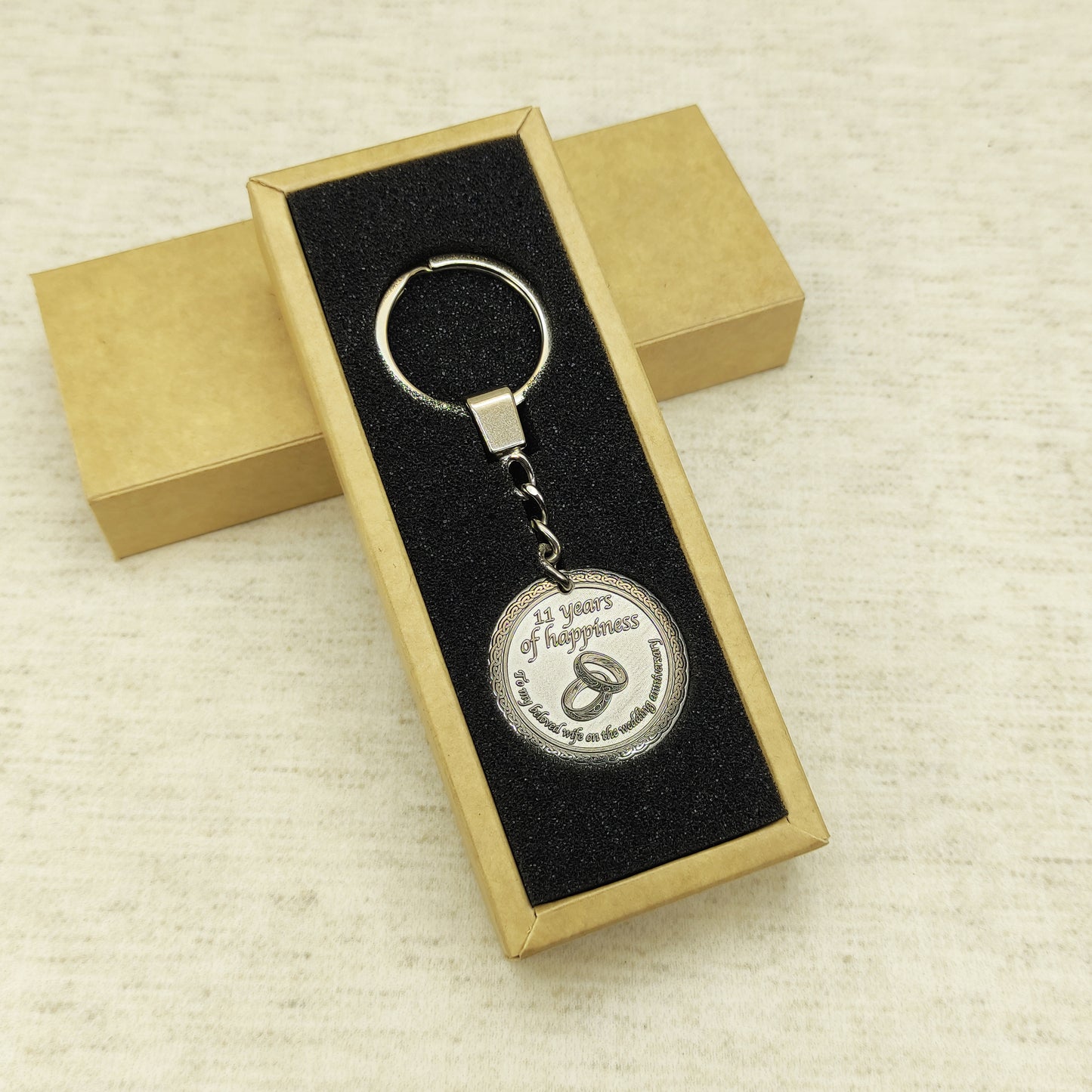 Brass anniversary keychain presented in a minimalist gift box with black foam insert, high-quality personalized metal gift for 11 years of marriage.