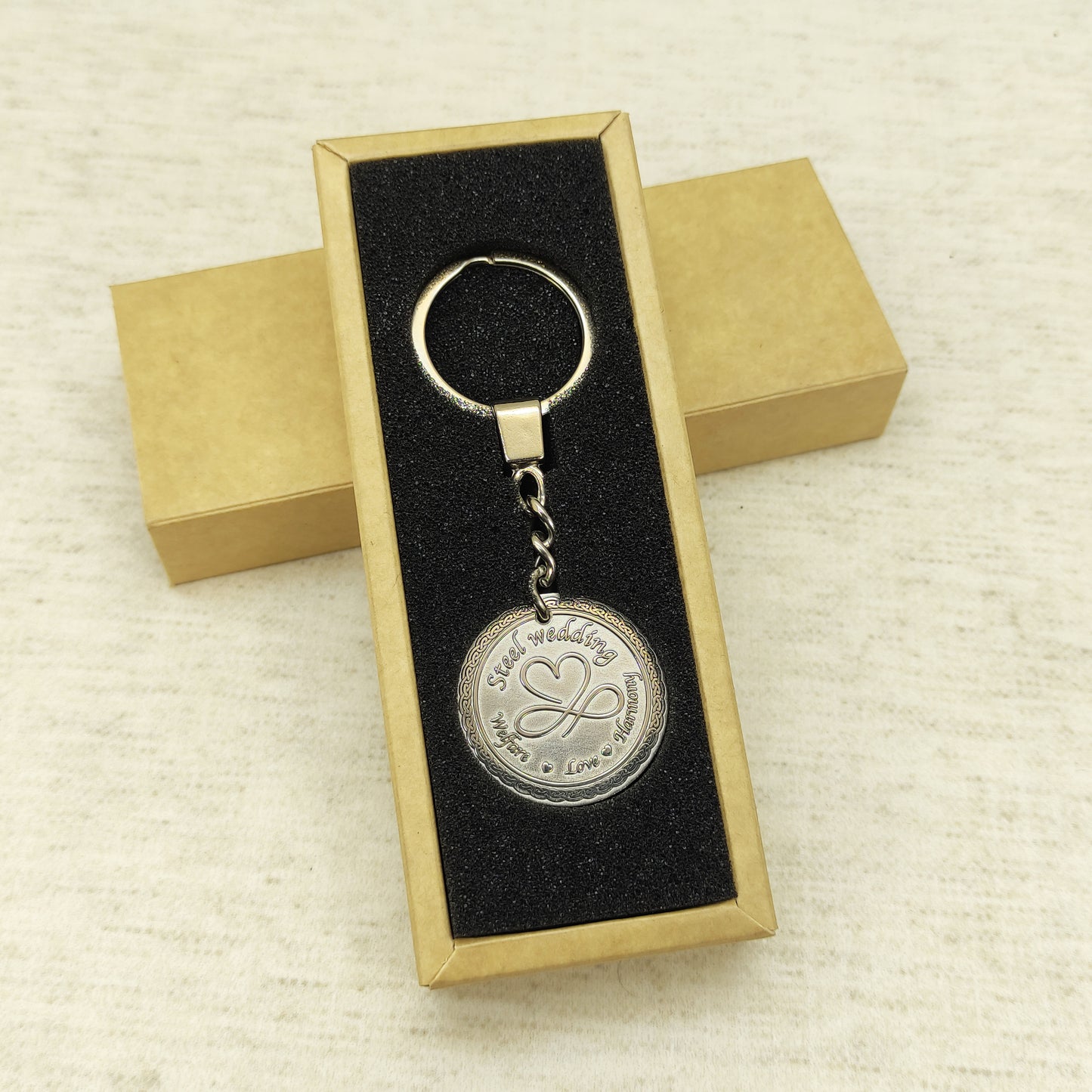 Customized steel anniversary keychain presented in an elegant black gift box with foam insert.