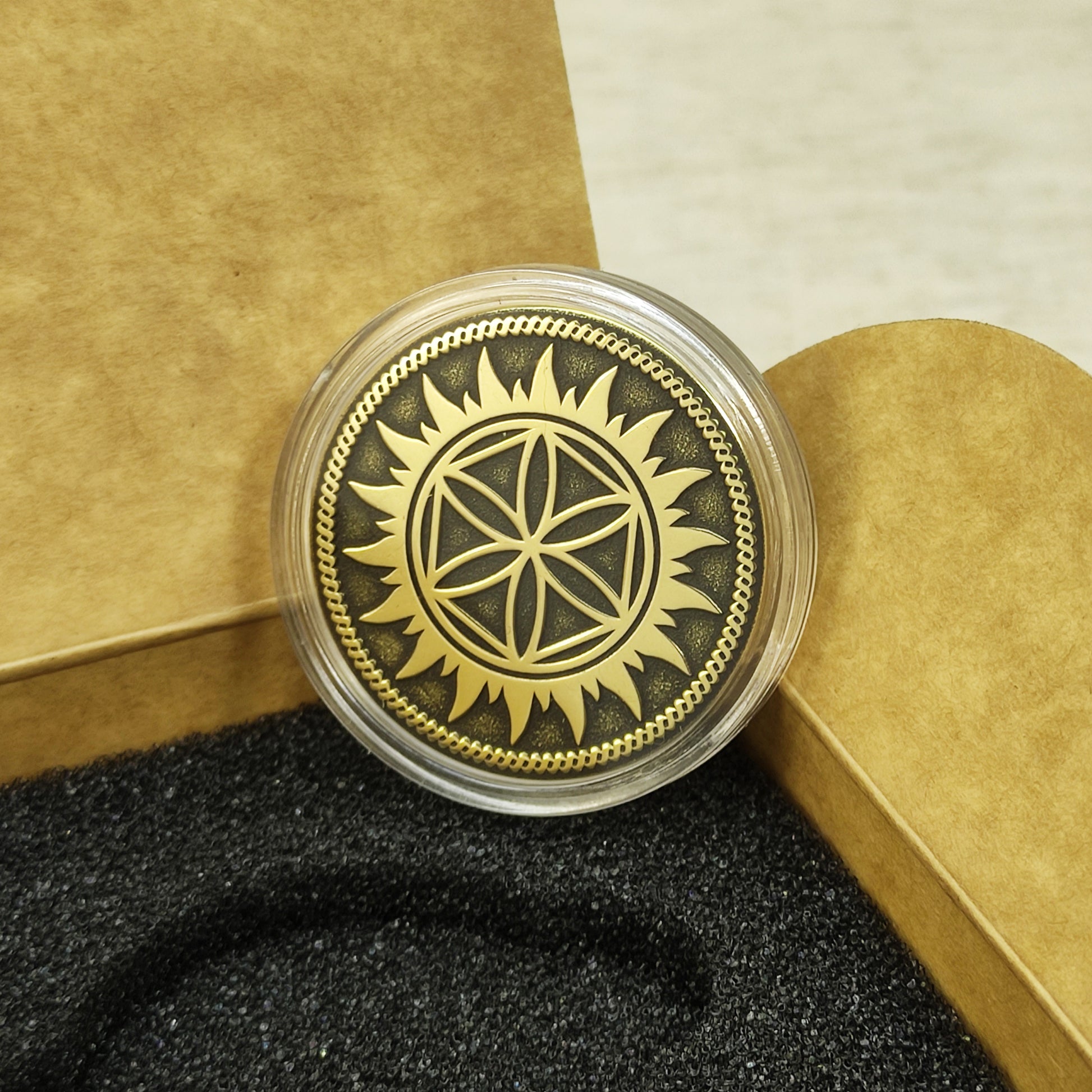 Perun Star brass talisman coin protected in a clear acrylic capsule showing detailed geometric engraving and patina.