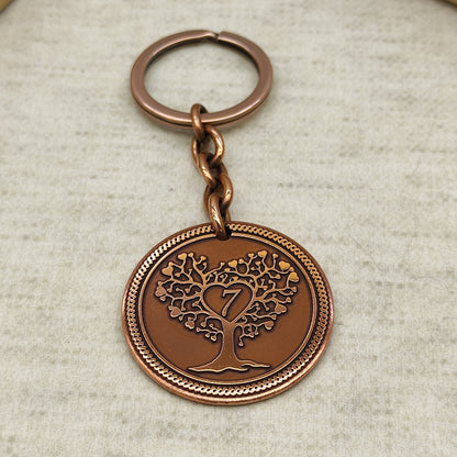 Top down view of handcrafted copper keychain for 7th wedding anniversary with antique patina and sturdy metal ring attachment.