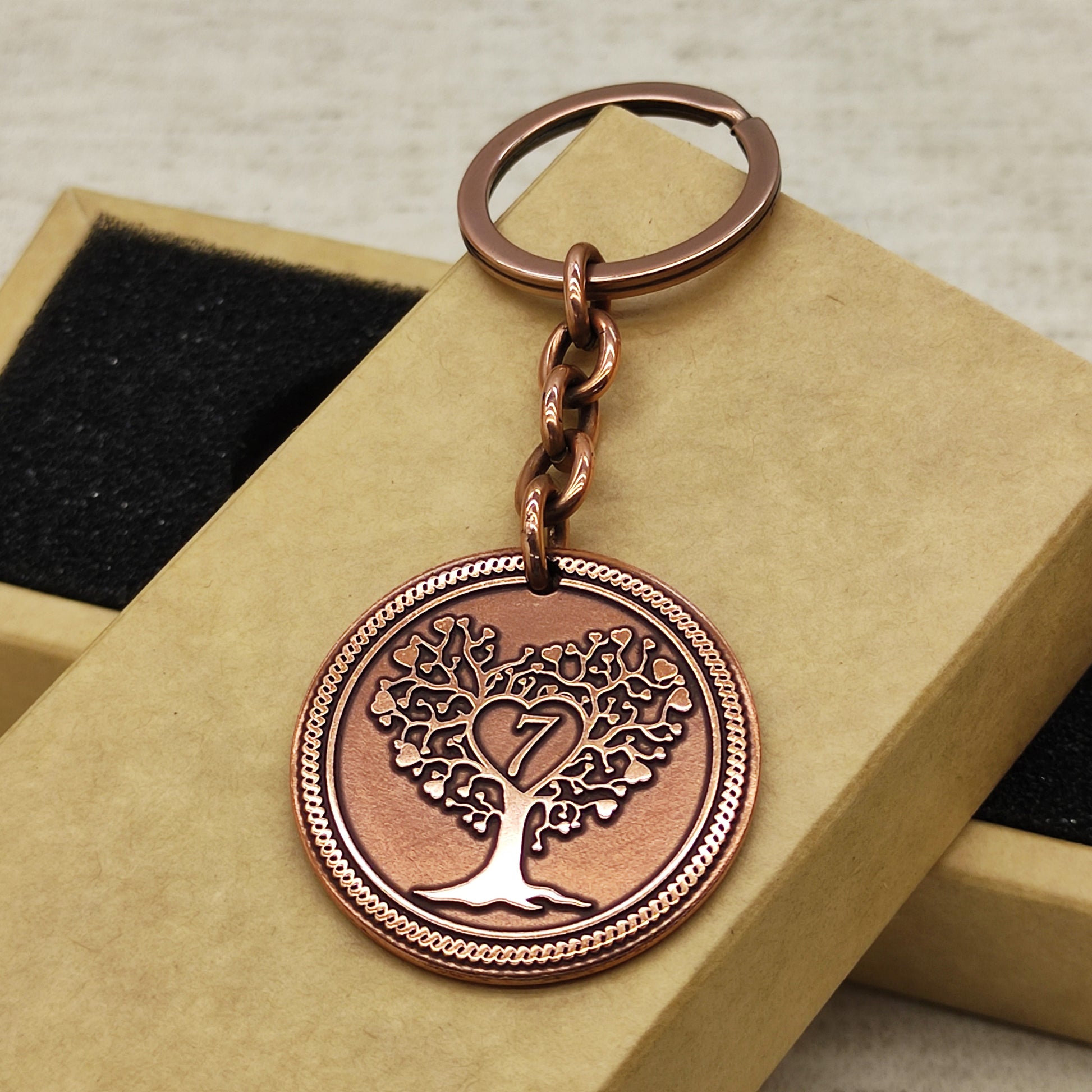 Full view of 7th anniversary personalized copper coin keychain placed on a premium black velvet lined gift box.