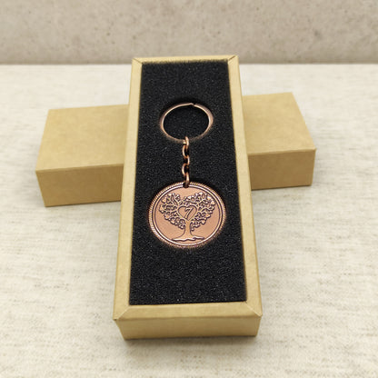 Vertical shot of a custom engraved copper anniversary keychain in a gift package, showcasing the contrast of metal and dark lining.