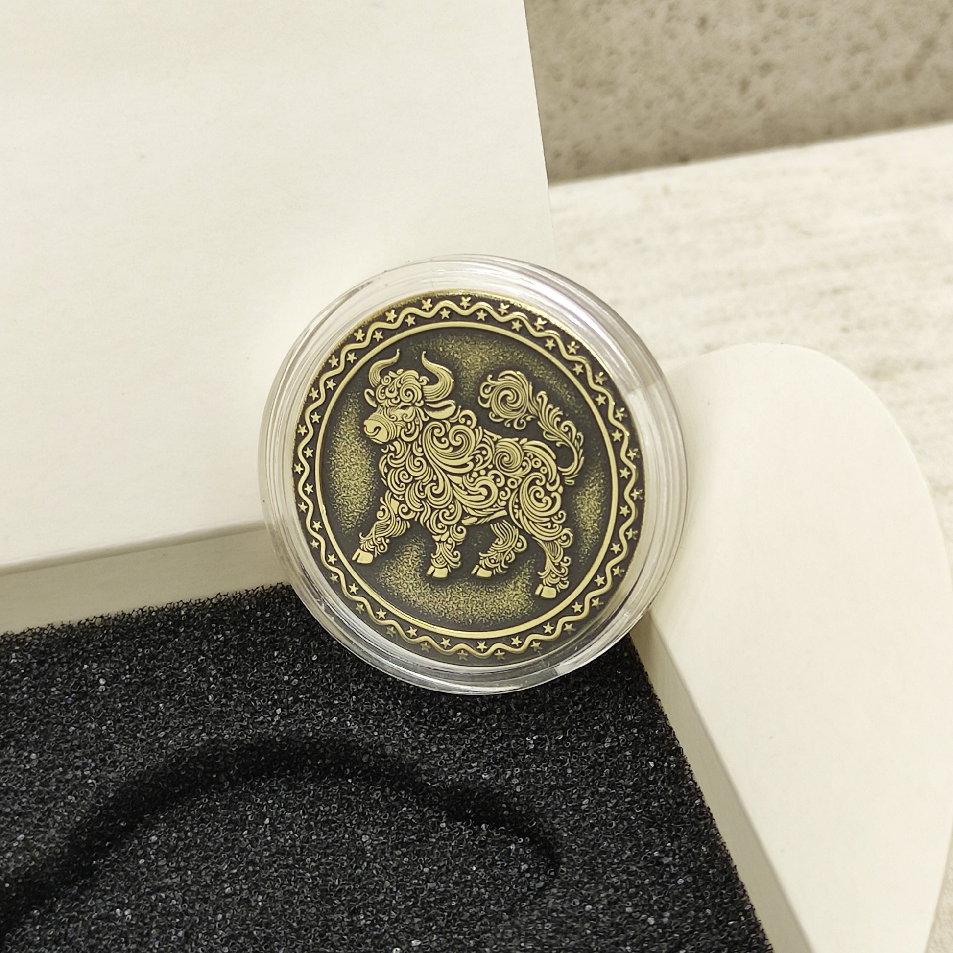 Macro photo of the brass Ox coin in a protective capsule, highlighting the intricate dark recessed patina engraving for high contrast.